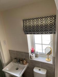 ein Badezimmer mit Waschbecken und einem Fenster mit Spiegel in der Unterkunft Comfortable 5 - Guest Abode - In Quiet Village in Grantham + 15 Fotos