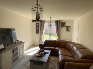 ein Wohnzimmer mit Ledercouch und Fernseher in der Unterkunft Comfortable 5 - Guest Abode - In Quiet Village in Grantham