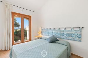 a bedroom with a blue and white bed and a window at Garden Delight House in Chia