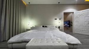 a bedroom with a large white bed and a tv at غرفة بجاكوزي مع صالة 1 من أرام ريزدنس by ARAM Residence in Aţ Ţuwayr
