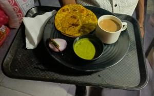 bandeja con un plato de comida y una taza de café en hotel Sachin INN, en Etāwah