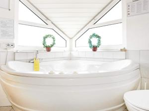 a white bathroom with a tub and two windows at 10 person holiday home in Thisted-By Traum in Klitmøller