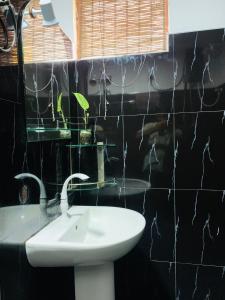 a bathroom with a sink and a black tiled wall at KAIMANA HOUSE - 3 Min walk to the beaches in Tangalle +12 photos