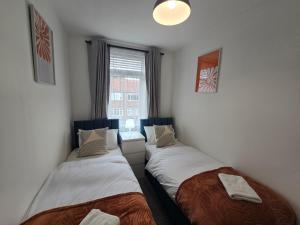 Dos camas en una habitación pequeña con ventana. en Spacious 3bedroom Apartment-Short and Long Stays-Contractors and Families, en Dunston