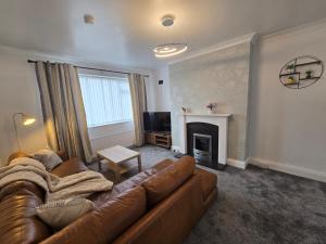 Una sala de estar con un sofá de cuero y una chimenea. en Spacious 3bedroom Apartment-Short and Long Stays-Contractors and Families, en Dunston