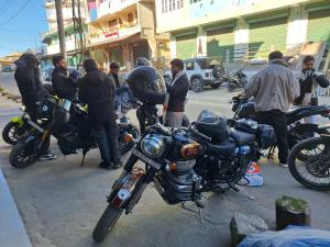 a group of people standing around motorcycles on a street at TN's Basecamp Hostel in Tawang +2 photos