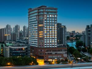 a tall building with lights on in a city at Mercure Shanghai Global Harbour in Shanghai