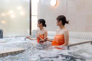 two women sitting in a hot tub at Kur and Hotel Shinshu in Shiojiri
