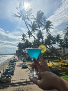 Eine Person, die vor dem Strand ein blaues Getränk in der Hand hält. in der Unterkunft Homestay Trương Khang Ocean in Ấp Thiện Sơn