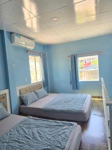 zwei Betten in einem Zimmer mit blauen Wänden in der Unterkunft Homestay Trương Khang Ocean in Ấp Thiện Sơn + 18 Fotos
