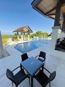 eine Terrasse mit Tisch und Stühlen neben einem Swimmingpool in der Unterkunft Peaceful Panglao Escape for Families Couples in Dao