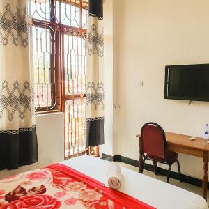 a bedroom with a bed and a desk and a television at Lesilale Hotel in Morogoro