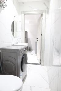 a white bathroom with a washing machine in it at ريلاكس للاجنحة الفندقية in Amman