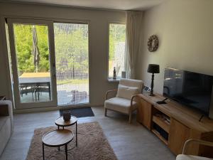 Una sala de estar con un televisor de pantalla plana y una silla. en Strand 104, en Hollum