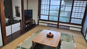 a living room with a table and some windows at ペットok 古民家ふるさと真鶴 in Manazuru