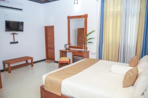 ein Schlafzimmer mit einem Bett, einem Spiegel und einer Kommode in der Unterkunft Ibbankatuwa Lake Resort in Dambulla