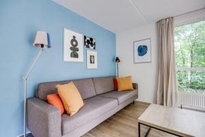 ein Wohnzimmer mit einer grauen Couch und blauen Wänden in der Unterkunft Zonnige luxe bungalow met grote tuin in Ewijk