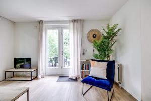 un salon avec une chaise bleue et une fenêtre dans l'établissement Zonnige luxe bungalow met grote tuin, à Ewijk