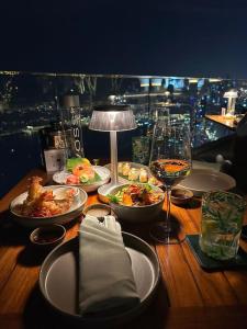een tafel met borden en een glas wijn bij Light Vesper Premium Hotel in Ho Chi Minh-stad
