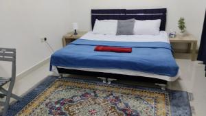 a bedroom with a bed with a blue blanket and a rug at Bait Alhoor in Muscat +2 photos