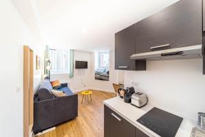 Una cocina y una sala de estar con un sofá. en Quiet & Comfortable Studio Near Lyon Sainte-Foy-lès-Lyon, en Sainte-Foy-lès-Lyon