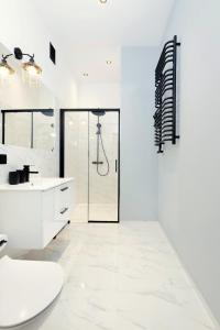 a white bathroom with a shower and a sink at Roomy apartment Łobzowska Street in Kraków +26 photos