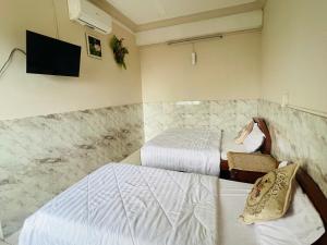 a bedroom with two beds and a tv on the wall at An Long Hotel in Ấp Ðông An (1)