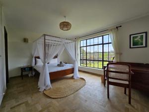 a bedroom with a canopy bed and a large window at Kipepeo Villa in Naivasha