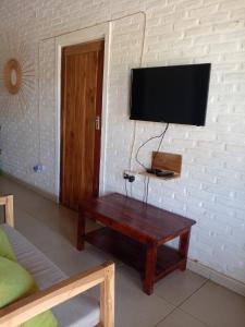 ein Wohnzimmer mit einem Tisch und einem TV an der Wand in der Unterkunft Katawa Cottage in Monkey Bay