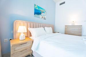 een slaapkamer met een wit bed en een nachtkastje met een lamp bij Sustainable Luxury 1BR Reem Island Stay 4 Guest in Abu Dhabi +29 foto's