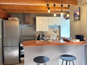 a kitchen with two stools and a counter with a refrigerator at La Brillance in Savignac-les-Ormeaux