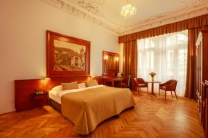 a bedroom with a bed and a table with chairs at Hotel Golden Lamb in Karlovy Vary