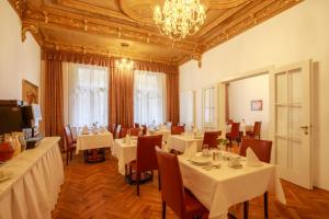 a restaurant with white tables and chairs and a chandelier at Hotel Golden Lamb in Karlovy Vary