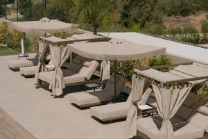 a group of chairs and umbrellas on a patio at Anassa Villa, with 110m2 Pool, Emerald Gardens, Wellness & Sports, By ThinkVilla 