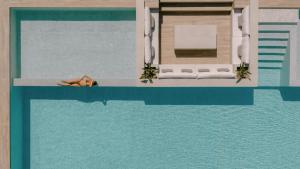 a woman laying on the edge of a swimming pool at Anassa Villa, with 110m2 Pool, Emerald Gardens, Wellness & Sports, By ThinkVilla 