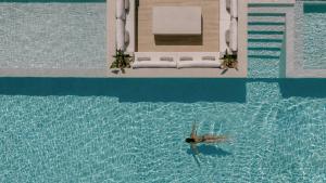 a person in the water in a swimming pool at Anassa Villa, with 110m2 Pool, Emerald Gardens, Wellness & Sports, By ThinkVilla  +83 photos