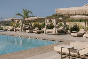 a pool with lounge chairs and umbrellas next to a resort at Anassa Villa, with 110m2 Pool, Emerald Gardens, Wellness & Sports, By ThinkVilla 