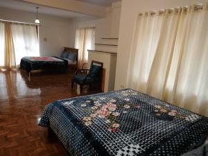 a bedroom with a bed and a chair and curtains at Kodai ARYASREE in Kodaikānāl +9 photos