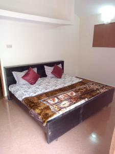 a bed with red pillows on it in a room at Kodai ARYASREE in Kodaikānāl