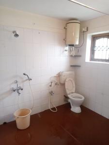 a bathroom with a toilet with a shower and a bucket at Kodai ARYASREE in Kodaikānāl