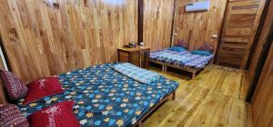 a bedroom with two beds in a room with wooden walls at Trạm Thẩm Lé in Văn Chấn