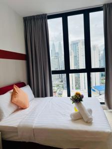 une chambre d'hôtel avec un lit avec une fenêtre avec des fleurs dessus dans l'établissement Majestic residence KLCC Luxury Pool, à Kuala Lumpur