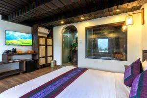 a bedroom with a large bed and a flat screen tv at Sapana Mountain Retreat in Sapa