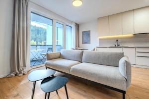 a living room with a couch and a kitchen at Apartmán s výhľadom na Vysoké Tatry a les in Svit +30 photos