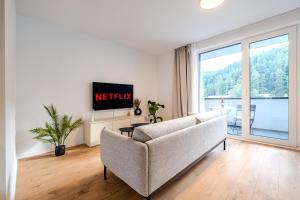 a living room with a couch and a tv at Apartmán s výhľadom na Vysoké Tatry a les in Svit