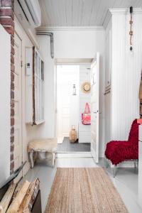 a white hallway with a red chair and a door at Hirsihuvi 1826 in Oulu