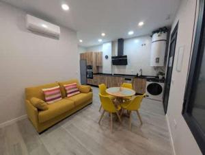 a living room with a yellow couch and a table and chairs at Apartamento Turistico NC in Cáceres