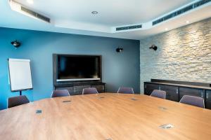a conference room with a large wooden table and a tv at Premier Inn Stuttgart Bad Cannstatt in Stuttgart