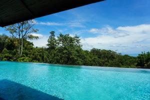 a pool with blue water and trees in the background at Hidden Gardens Resort, Davao in Davao City +56 photos