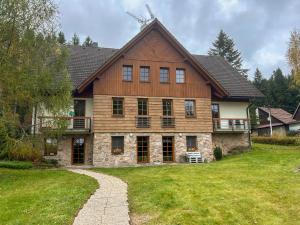 une grande maison en bois avec une pelouse dans l'établissement Apartmán v Srdci hor - Říčky v Orlických horách, à Říčky